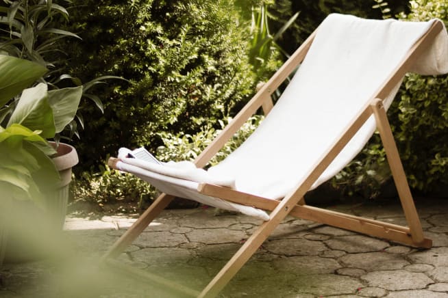 A deck chair in a patio garden surrounded by green outdoor plants