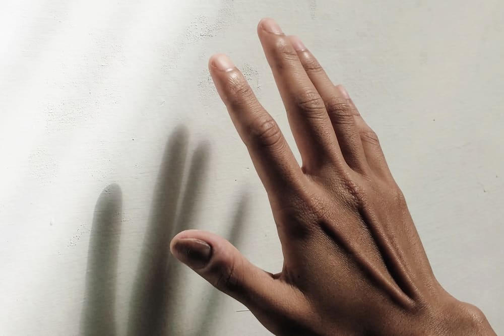 A hand near a wall, casting a shadow