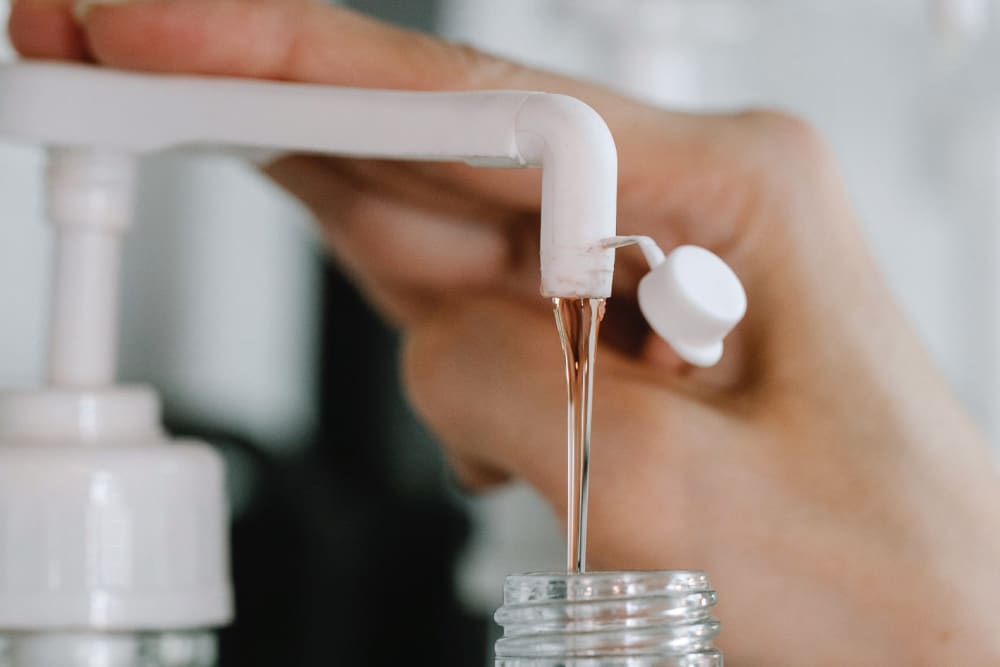 Dish soap being squeezed into a smaller plastic bottle